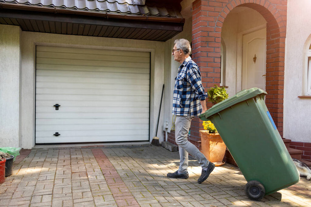 Senior man taking out garbage - Foto, afbeelding
