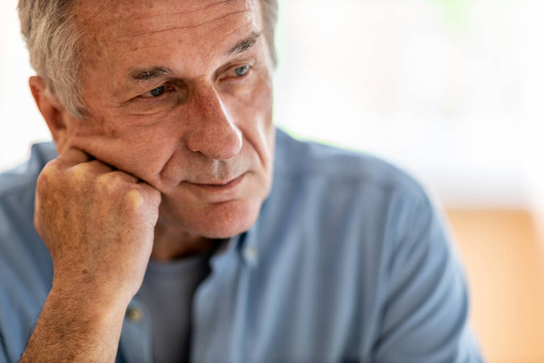 Oudere man ziet er verdrietig uit thuis - Foto, afbeelding