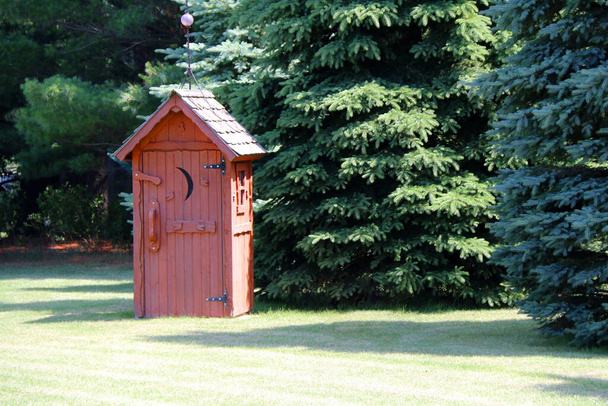 a rural red outhouse privy toilet building in a sunny forest glade - Photo, Image