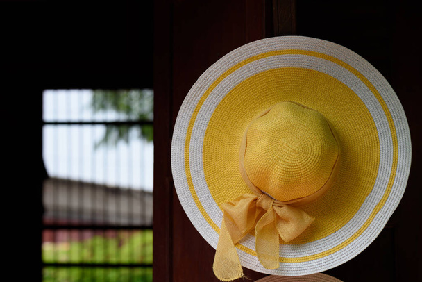 Желтая шляпа ручной работы висит на деревянной стене
 - Фото, изображение
