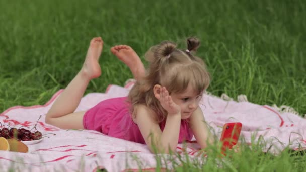 Víkend na pikniku. Dívka na trávě louka hrát online hry na mobilním telefonu. Sociální síť, chatování - Záběry, video