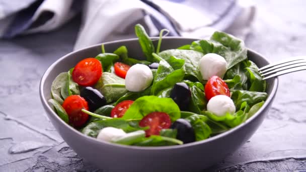 Вегетаріанська і органічна харчова концепція. Італійський або середземноморський салат. Tomato mozzarella basil листки чорні оливки і оливкова олія обертаються - Кадри, відео