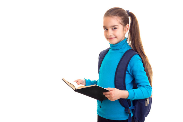 Schoolgirl with book in hands looking in camera - Фото, зображення