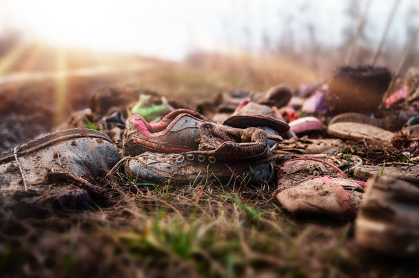 Zapatillas de deporte viejas abandonadas en el suelo de grava, zapatos gastados, enfoque suave
. - Foto, Imagen