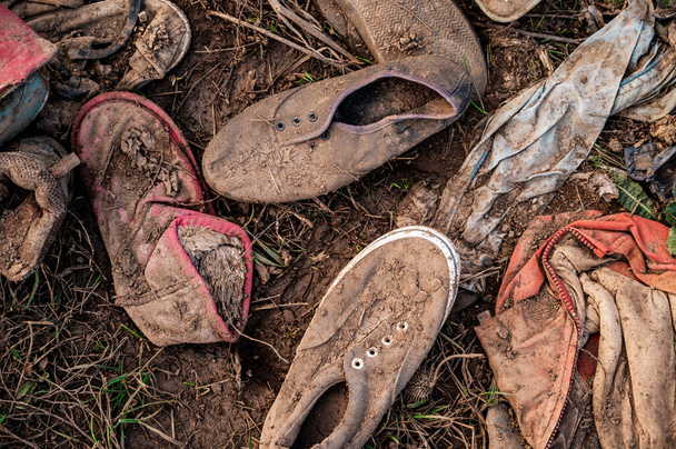 Старые кроссовки, брошенные на гравийном полу, ботинки, мягкий фокус
. - Фото, изображение