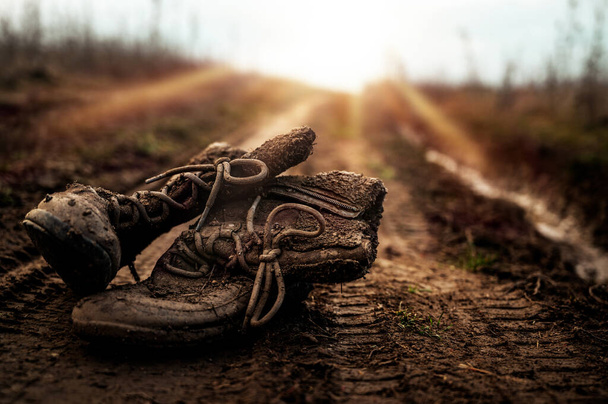 Старі кросівки, залишені на гравійній підлозі, зношені туфлі, м'який фокус
. - Фото, зображення