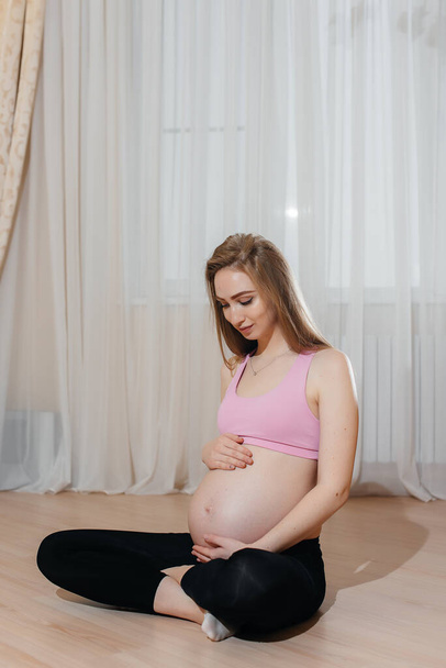 A pregnant girl does yoga at home. Health - Fotografie, Obrázek