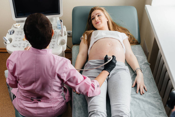 A pregnant girl gets an ultrasound of her abdomen at the clinic. Medical examination - Foto, Bild