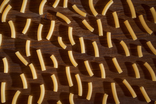 Keltainen pasta on ruskealla pöydällä. Laadukas kuva - Valokuva, kuva