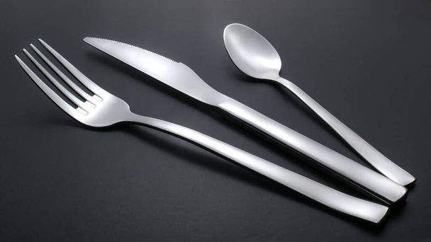 coltello, forchetta e cucchiaino su fondo nero - Foto, immagini