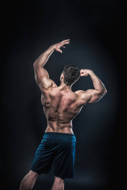 Sexy young athlete posing on a black background in the Studio. Fitness, bodybuilding - 写真・画像