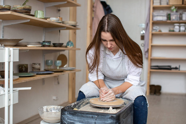A female potter produces ceramic utensils from clay in a pottery workshop. - Photo, image