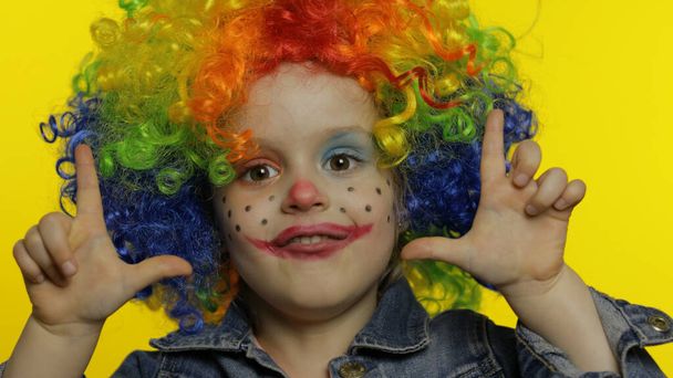 Kleine kind meisje clown in kleurrijke pruik vertelt iets interessants. Plezier hebben, lachen. Halloween - Foto, afbeelding