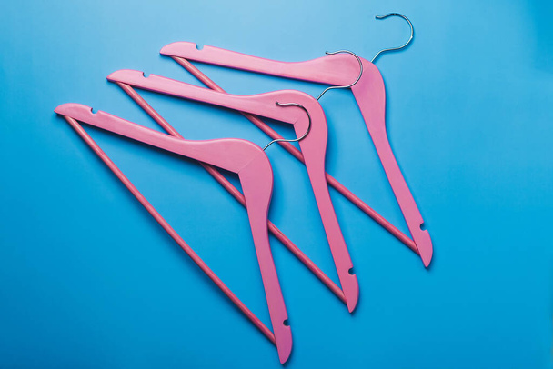 Pink empty wooden clothes hangers on pastel blue background. - Foto, immagini