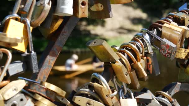 Love locks at a bridge in the Bastion Hill Park with a couple in a boat in the pilsetas kanal in Riga Latvia - Footage, Video