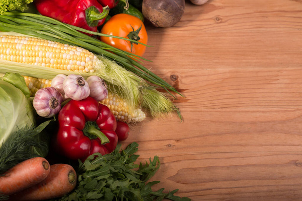 Asortyment świeżych surowych warzyw na drewnianym stole. Zdrowe organiczne lokalne jedzenie. Góra widok tło z pustą przestrzenią. - Zdjęcie, obraz