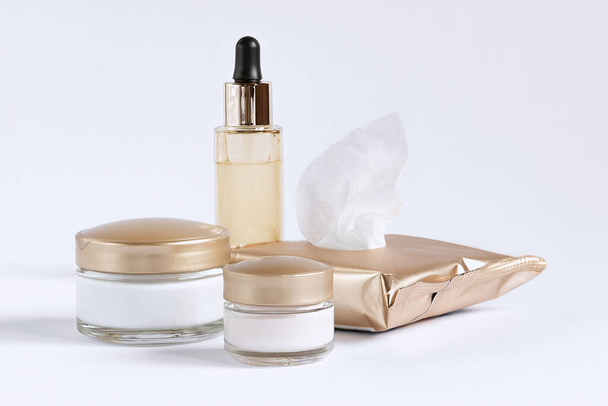 Een set voor de verzorging van de huid rond de ogen en de huid bestaande uit reinigingsdoekjes, glazen potjes crème en een fles met een serumpipet - Foto, afbeelding