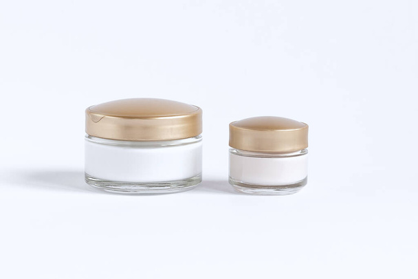 Een set voor huidverzorging rond de ogen en huid bestaande uit glazen potten met crème en serum - Foto, afbeelding