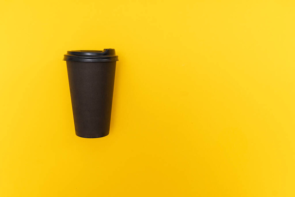 Coffee take away in black paper cup with black lid on yellow background - Photo, Image