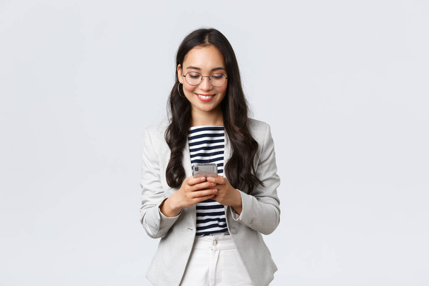 Business, finance and employment, female successful entrepreneurs concept. Businesswoman waiting for client, checking messages in smartphone, wearing glasses as looking at mobile screen - Photo, Image