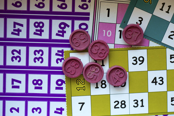 Tarjetas de juego de bingo coloridas y números sobre fondo blanco, primer plano, aislados
. - Foto, Imagen