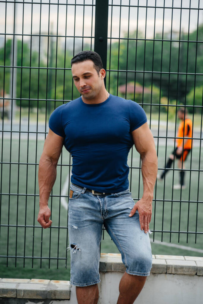Sports guy stands near the sports field. Bodybuilding - Photo, Image