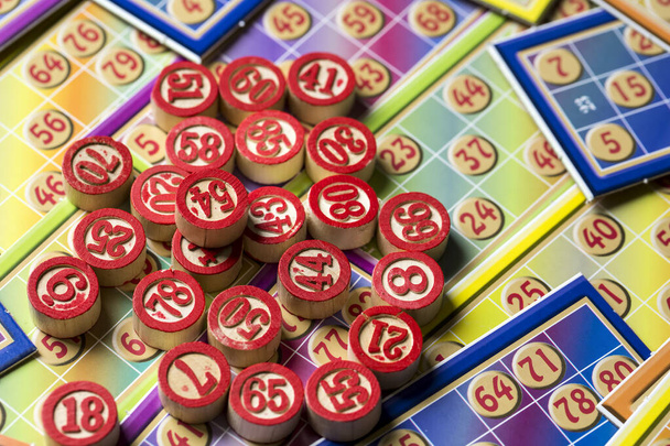 Πολύχρωμες κάρτες παιχνιδιών bingo και αριθμοί σε λευκό φόντο, κοντινό, απομονωμένο. - Φωτογραφία, εικόνα
