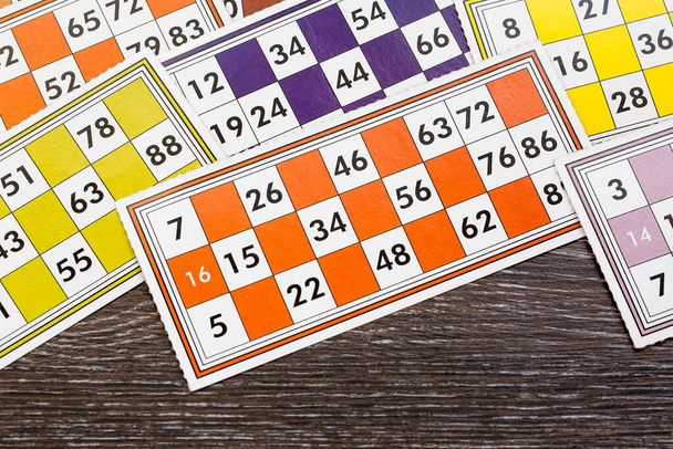 Bunte Bingo-Spielkarten und Zahlen auf weißem Hintergrund, Nahaufnahme, isoliert. - Foto, Bild