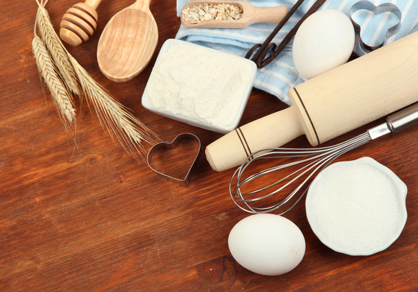 Cooking concept. Basic baking ingredients and kitchen tools on wooden table - Zdjęcie, obraz