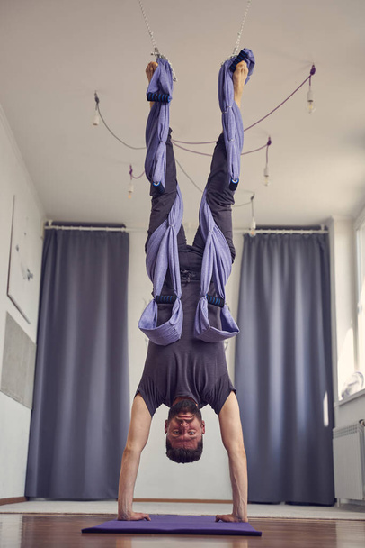 Athletic young man doing handstand yoga pose - Valokuva, kuva