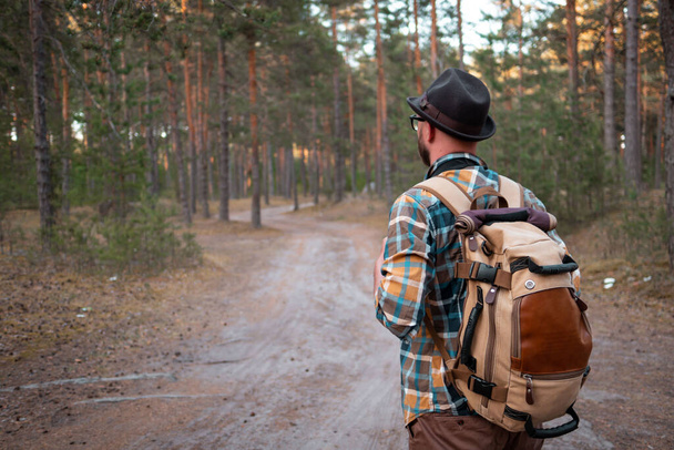 camping in the woods. a man in a hat with a backpack walks through the woods. - Φωτογραφία, εικόνα