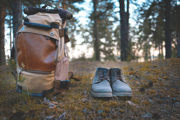 κάμπινγκ στο δάσος. μπότες και ένα σακίδιο σταθεί στο έδαφος με φόντο το δάσος - Φωτογραφία, εικόνα