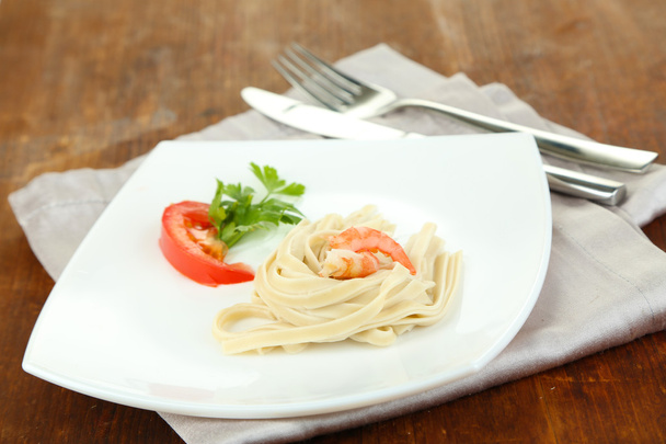 Pasta with shrimps on white plate, on wooden background - Foto, Imagen