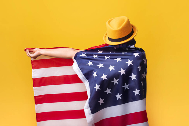 gir avec drapeau américain sur fond jaune, fille en chapeau à la mode avec drapeau américain - Photo, image