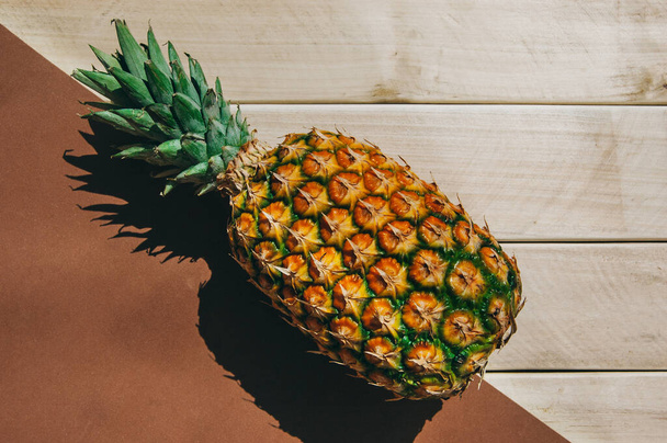 ripe juicy tropical pineapple on a yellow-white background. Space for text. Pineapple on a wooden table - Foto, afbeelding