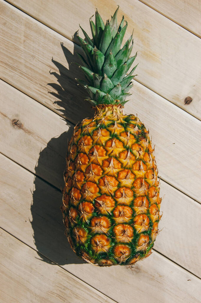 ripe juicy tropical pineapple on a yellow-white background. Space for text. Pineapple on a wooden table - Foto, Imagem