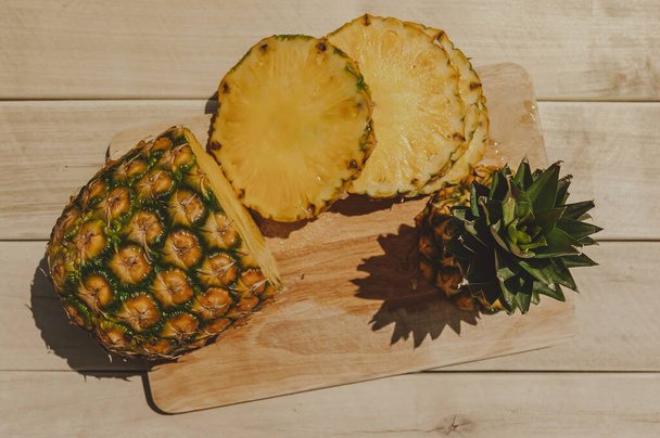 ripe juicy tropical pineapple on a yellow-white background. Space for text. Pineapple on a wooden table - Fotografie, Obrázek