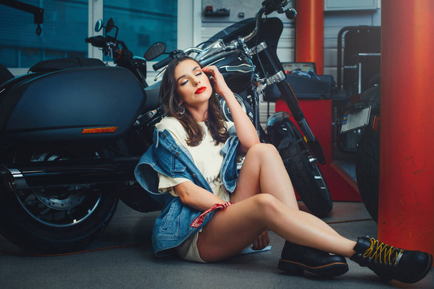 belle femme posant près d'une moto, tout en réparant une moto en service, image élégante pour un calendrier - Photo, image
