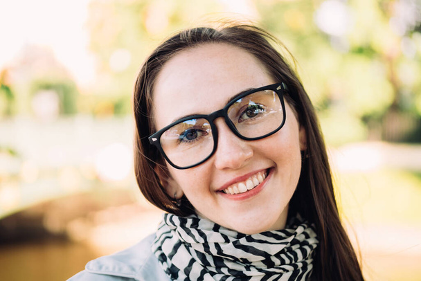 Portrait d'une jeune belle fille caucasienne avec des lunettes dans le parc - Photo, image