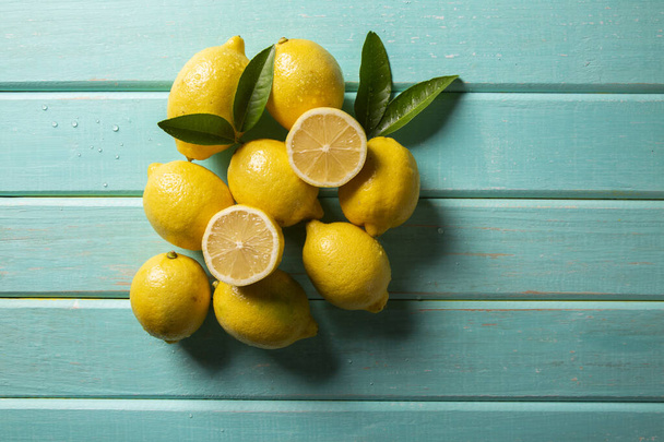 Yellow lemons on green wooden background - Foto, imagen
