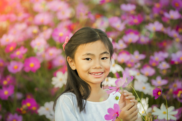 Pieni aasialainen tyttö puutarhassa
 - Valokuva, kuva