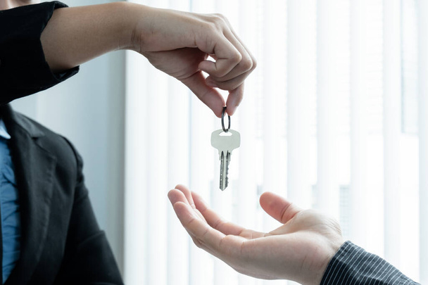 Agent nieruchomości przekazał klucz do domu nowemu właścicielowi po podpisaniu umowy najmu domu i wykupieniu oficjalnie ukończonego ubezpieczenia. - Zdjęcie, obraz