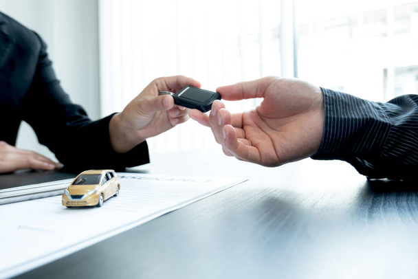 The car dealer advises the customer about insurance details and car rental information Ready delivers the keys after signing the rental contract. - Photo, Image