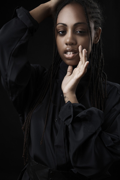 Porträt einer schönen jungen schwarzen Frau, die vor schwarzem Hintergrund posiert. - Foto, Bild