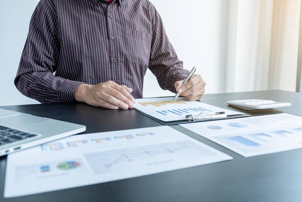 Egy férfi üzletember keze elemzi és kiszámítja az éves bevételeket és kiadásokat egy pénzügyi grafikonon, ami eredményeket mutat, hogy összegezze az egyenlegeket az irodában.. - Fotó, kép