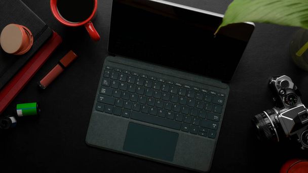 Вид зверху на жіночий стильний офісний стіл з цифровим планшетом, камерою, чашкою кави, книжками розкладів, косметикою та прикрасою на чорному столі
 - Фото, зображення