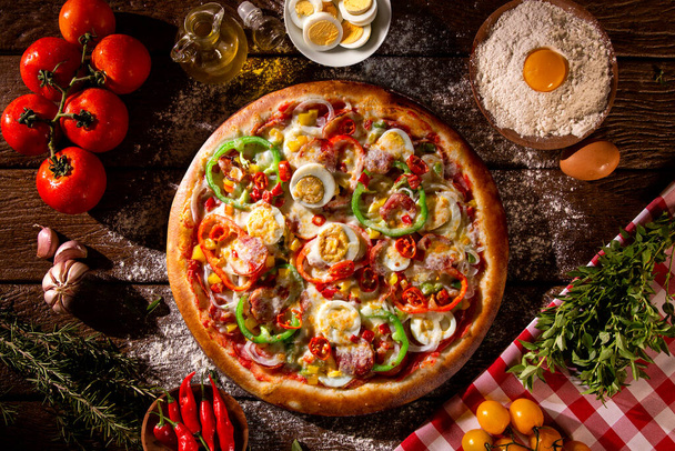 Pizza with red pepper, green pepper, eggs an pepperoni. Top view on wood background, close up. Traditional Brazilian Pizza - Foto, afbeelding