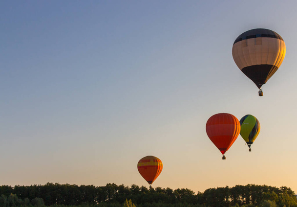 Kyjev, Ukrajina - 06 / 26 / 2020: Horkovzdušné balóny na čisté obloze nad lesem. Barevné balónky na pozadí letecké krajiny. Letní volný čas. Horkovzdušné balónky v letadle ráno. Koncept festivalu balónů. - Fotografie, Obrázek