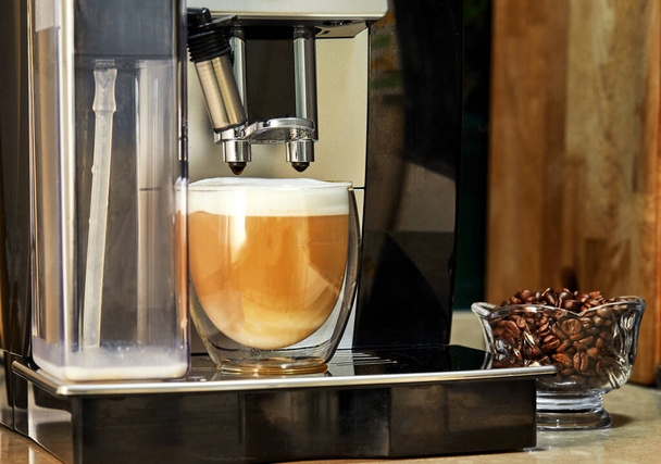 Kávovar dělá kávu cappuccino v průhledném šálku. Čerstvě uvařený koncept kávy. - Fotografie, Obrázek