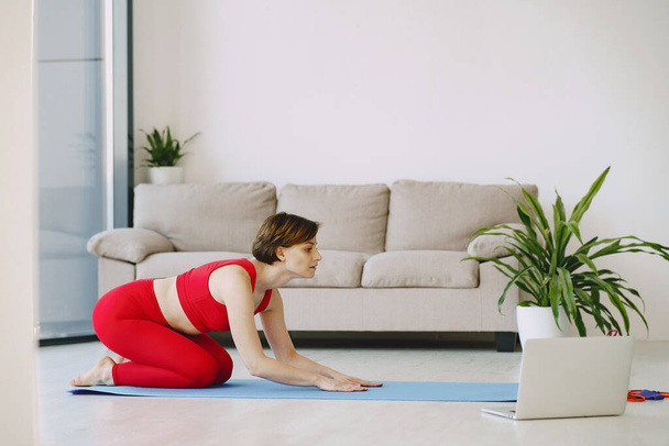 Girl in a red sports uniform make yoga at home - Foto, Imagen